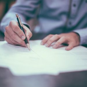 Técnico en marketing y publicidad a distancia de Asoenfermería, imagen de un estudiante con computadora y material de estudio.